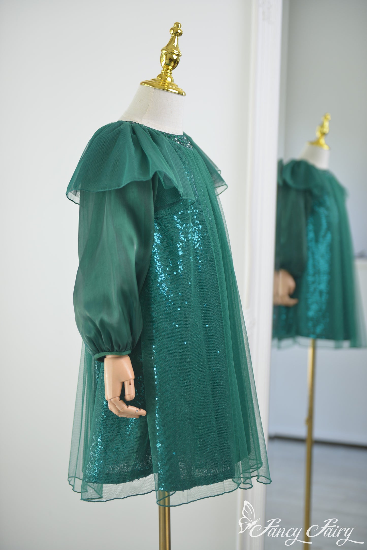 Side view of green tulle dress showing sleeve volume and sparkle detail.
