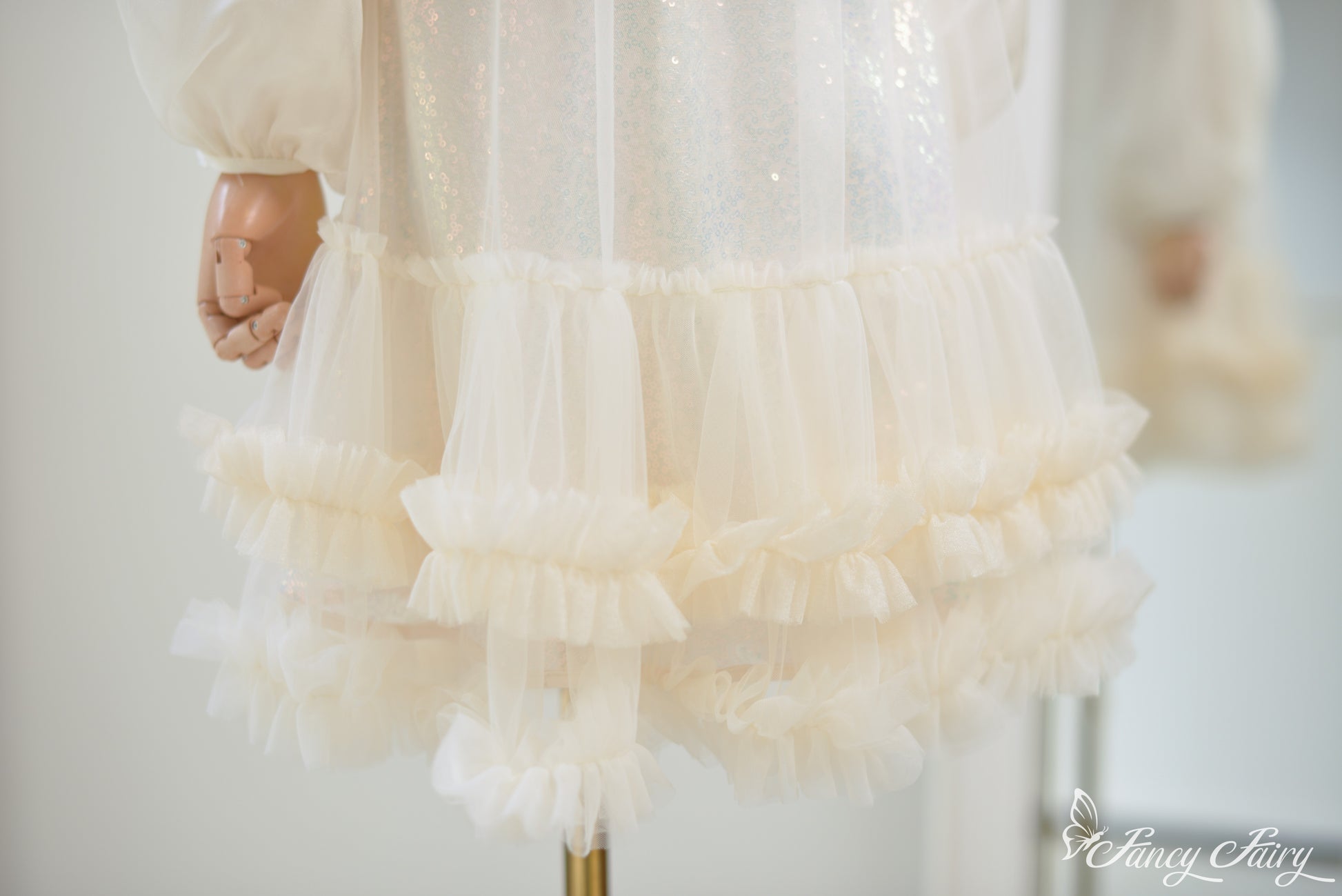 Zoom-in of ruffle layers and sequin sparkle on apricot mesh.