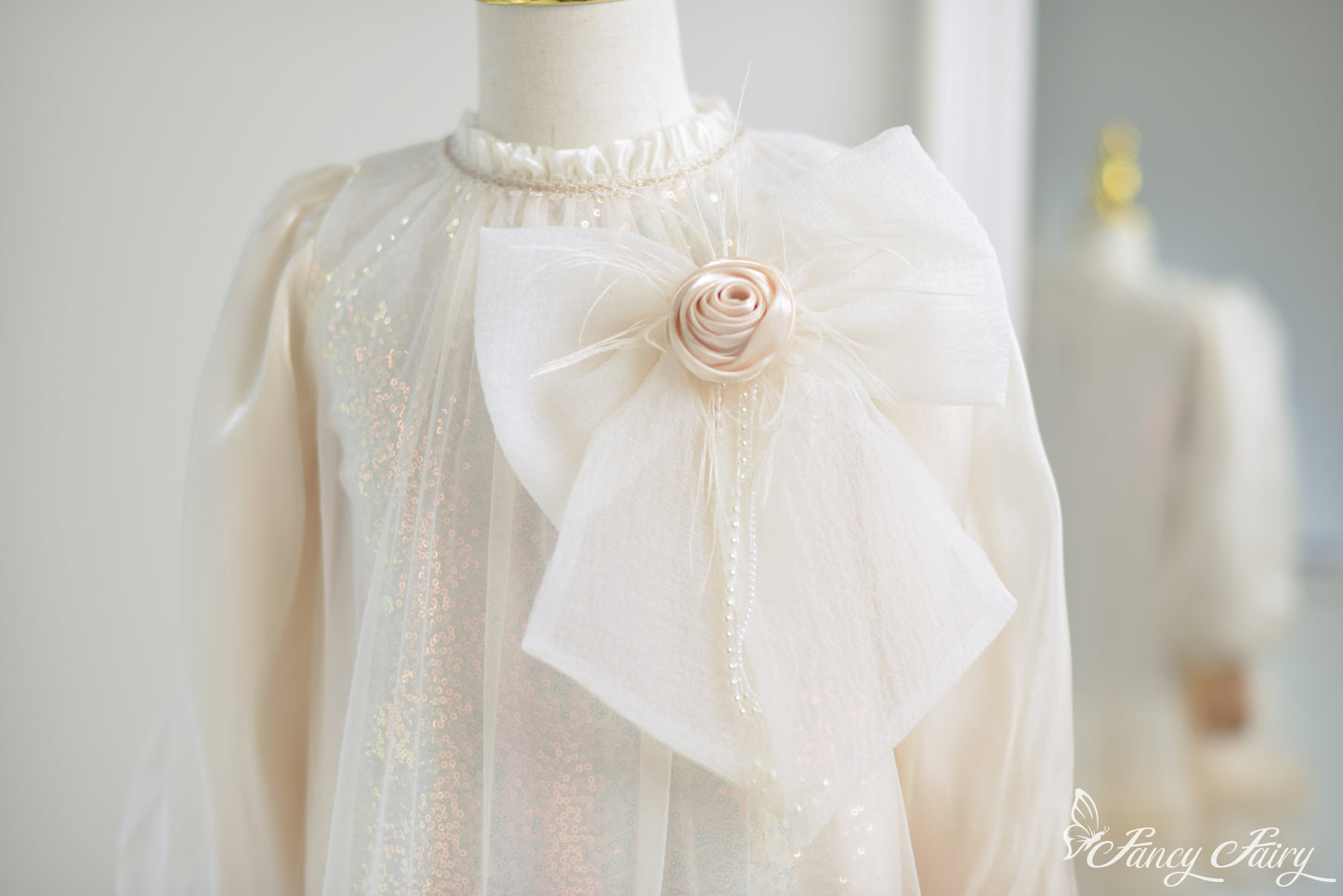 Close-up of fabric rose and layered bow with pearl and shimmer details.