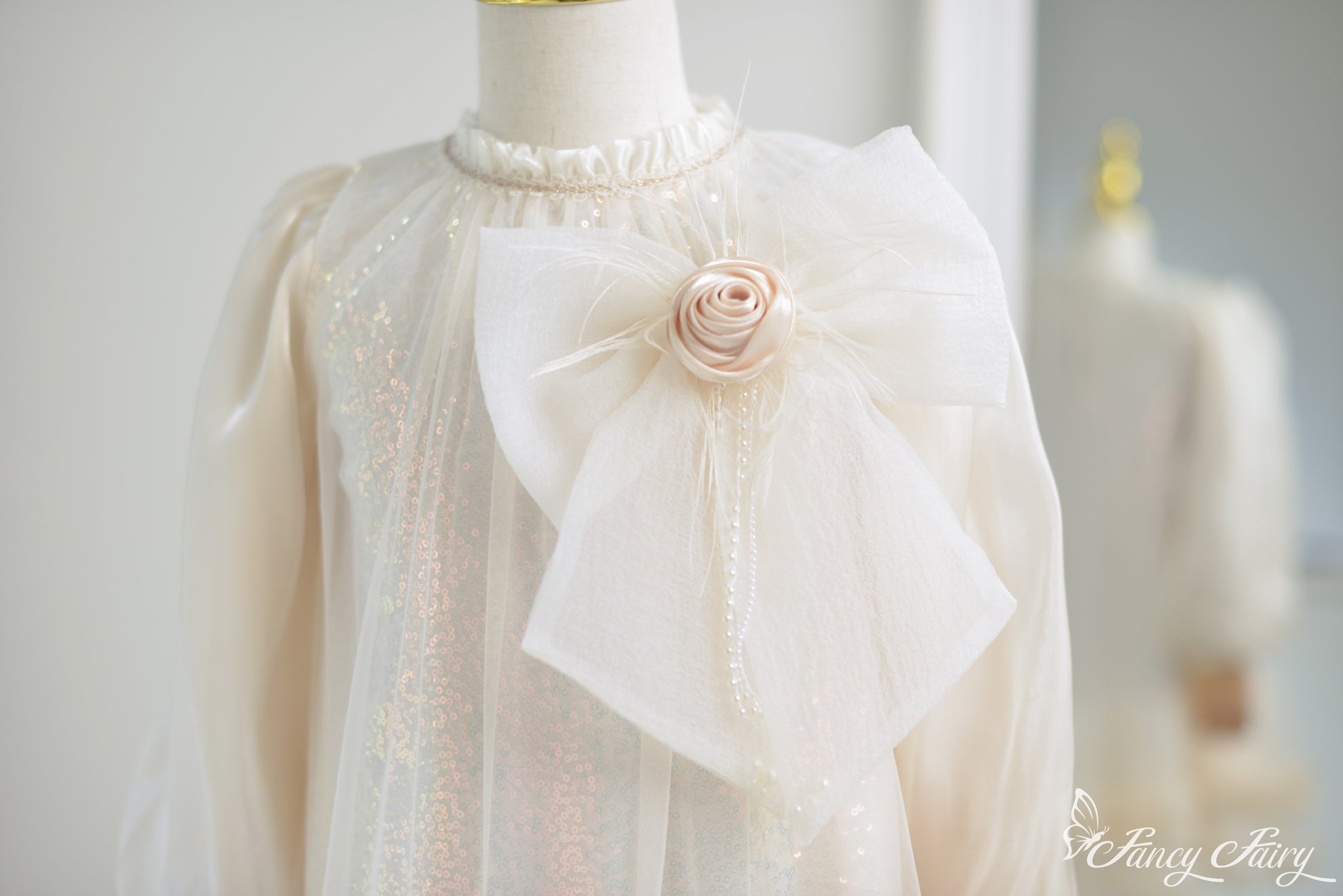 Close-up of fabric rose and layered bow with pearl and shimmer details.