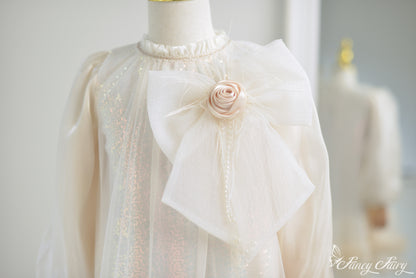 Close-up of fabric rose and layered bow with pearl and shimmer details.