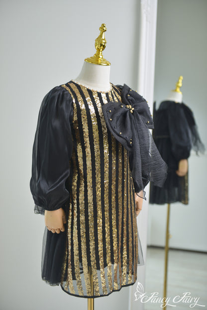 Side view of black and gold sequin dress with puff sleeves and bold black bow.