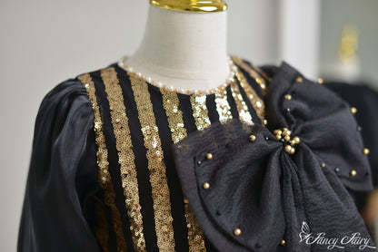 Zoom on black bow detail with gold pearls and textured fabric.