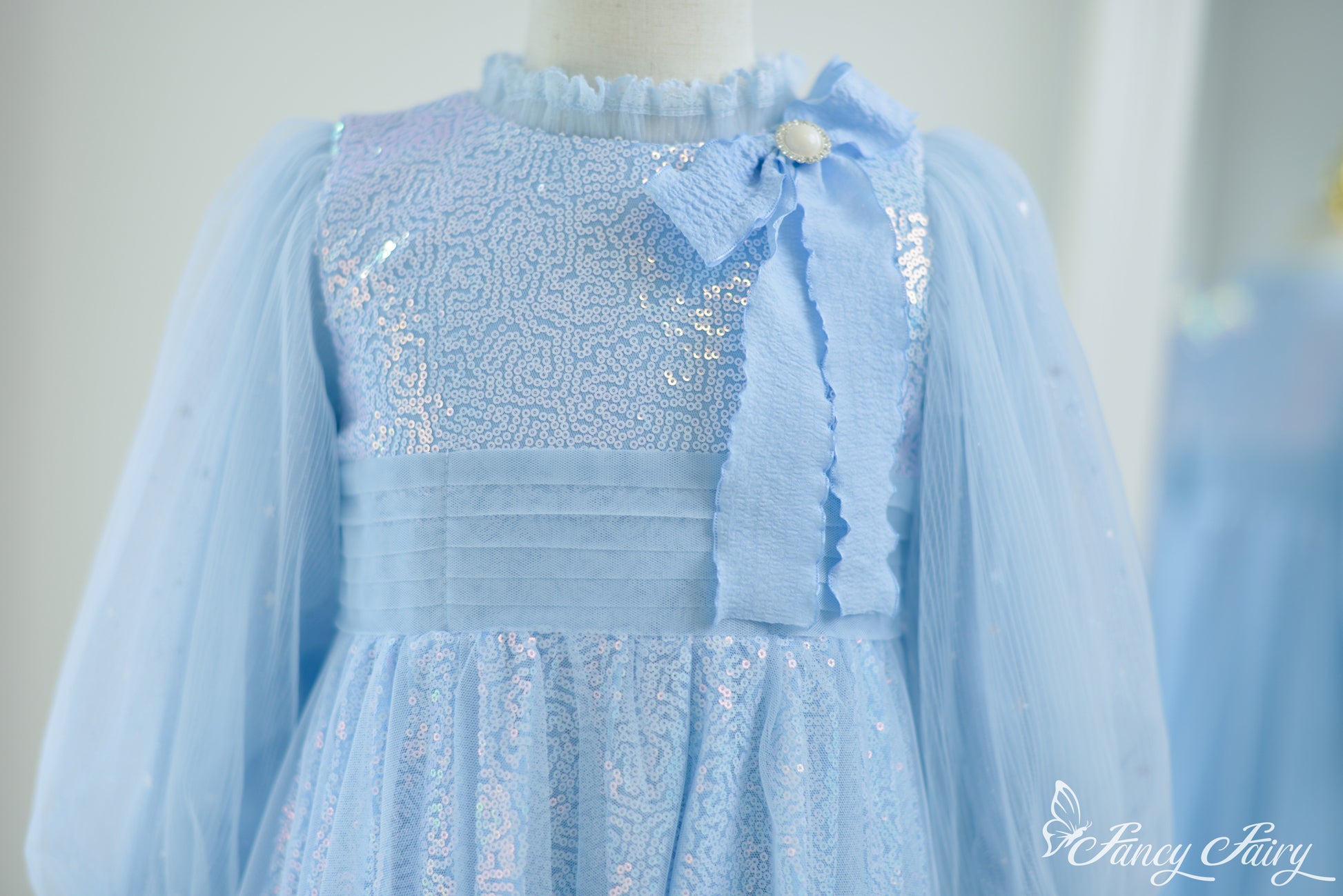 Close-up of glittery bodice with textured shimmer and soft blue ribbon bow.