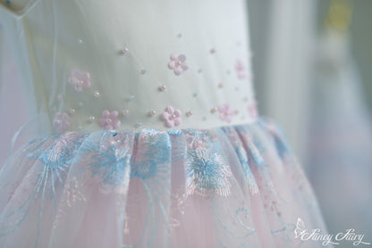 Detail of bodice embroidery and gathered waist seam with pink floral accents.