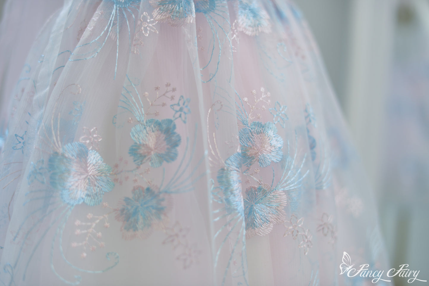 Close-up of skirt showing pastel blue floral patterns on sheer pink overlay.