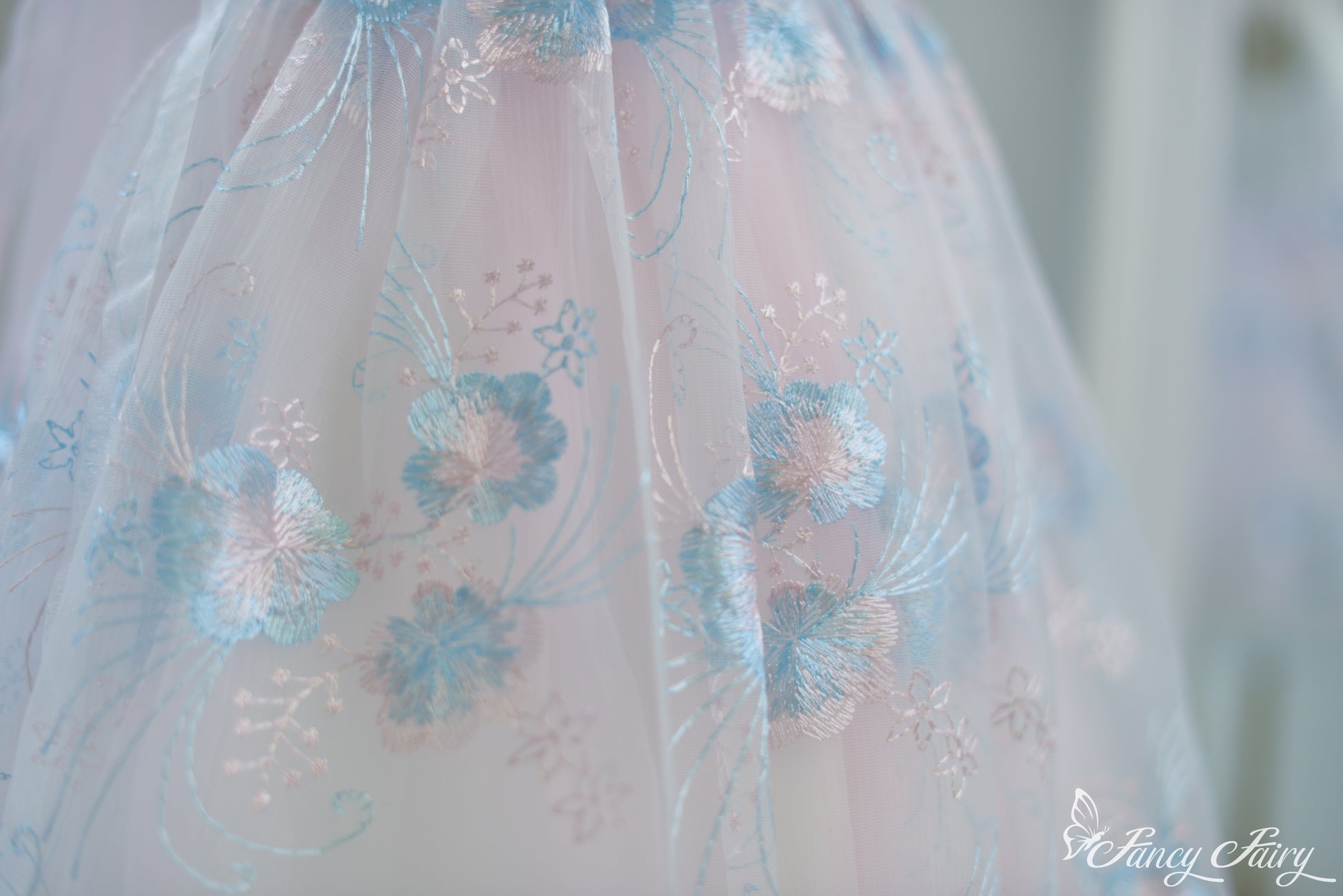Close-up of skirt showing pastel blue floral patterns on sheer pink overlay.