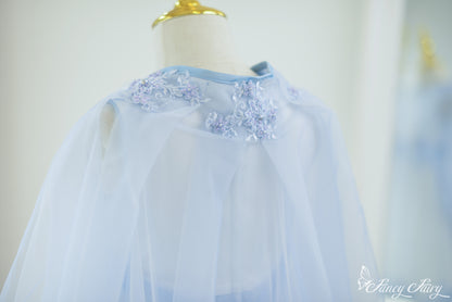 Back view showing cape drape and floral details on neckline.