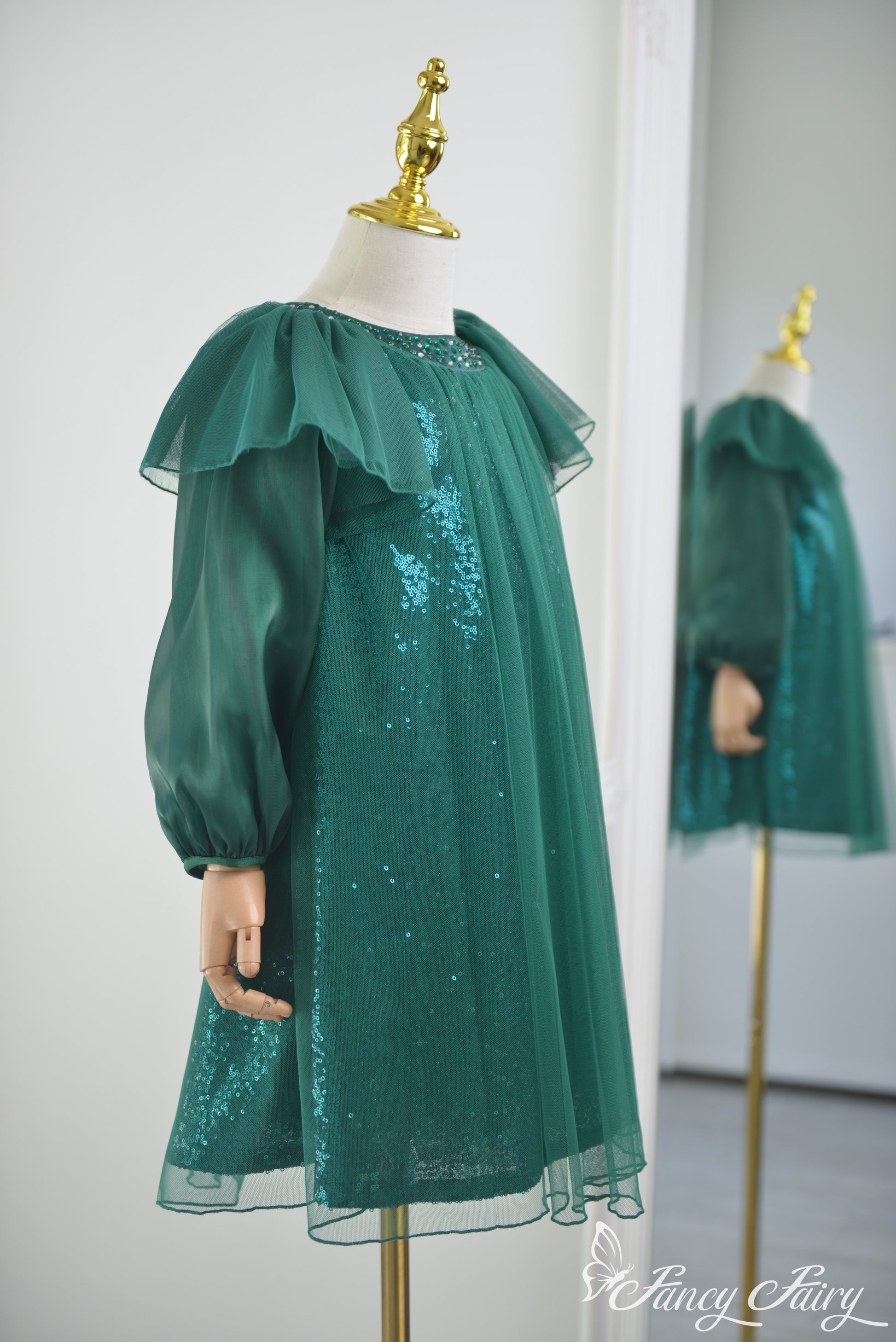 Side view of green tulle dress showing sleeve volume and sparkle detail.