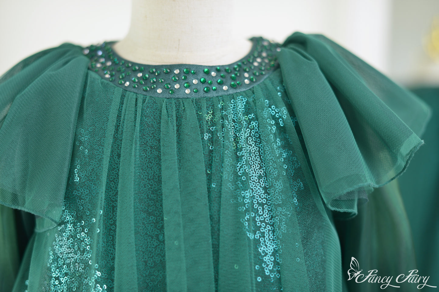 Close-up of beaded neckline with emerald rhinestones and layered mesh.