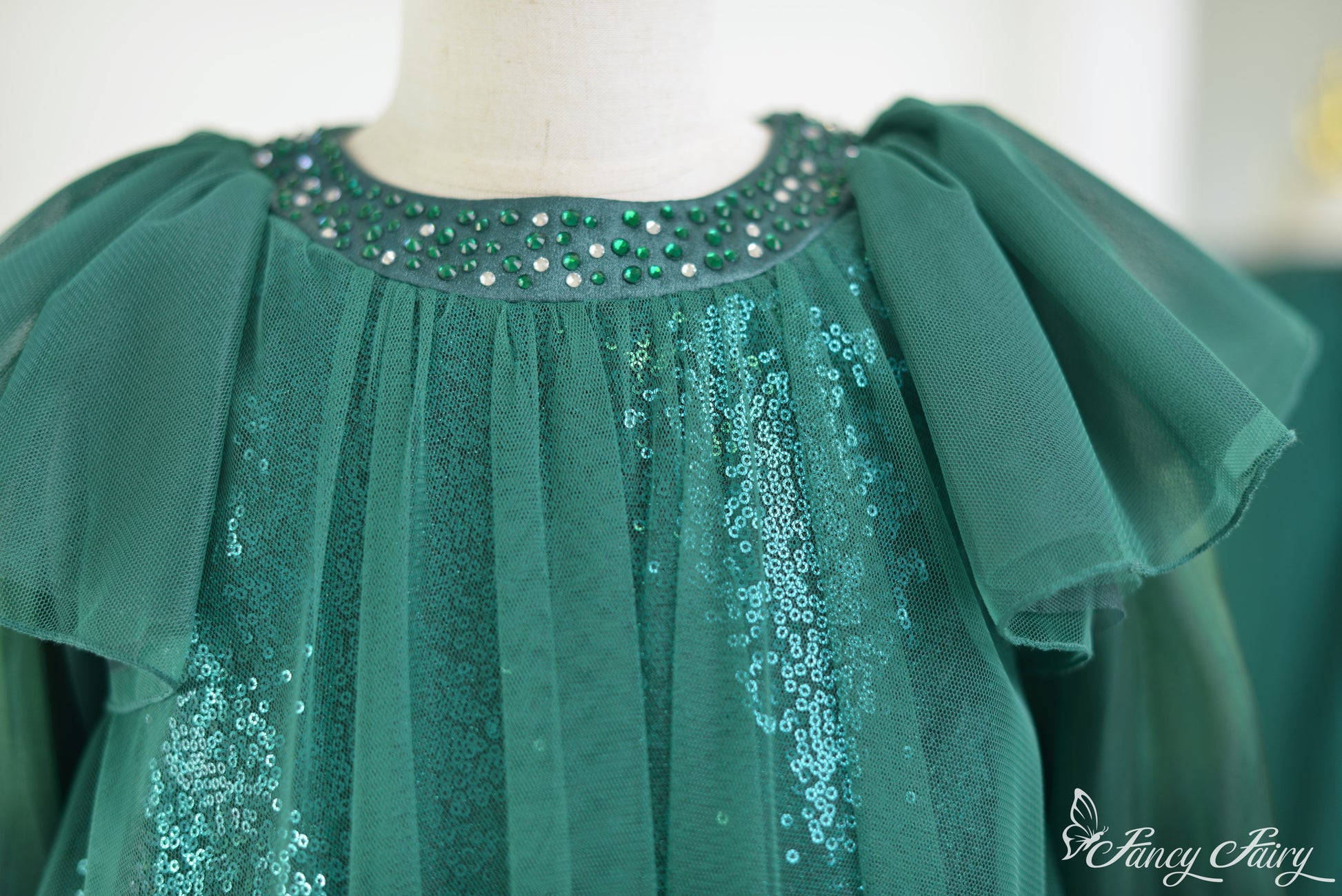 Close-up of beaded neckline with emerald rhinestones and layered mesh.