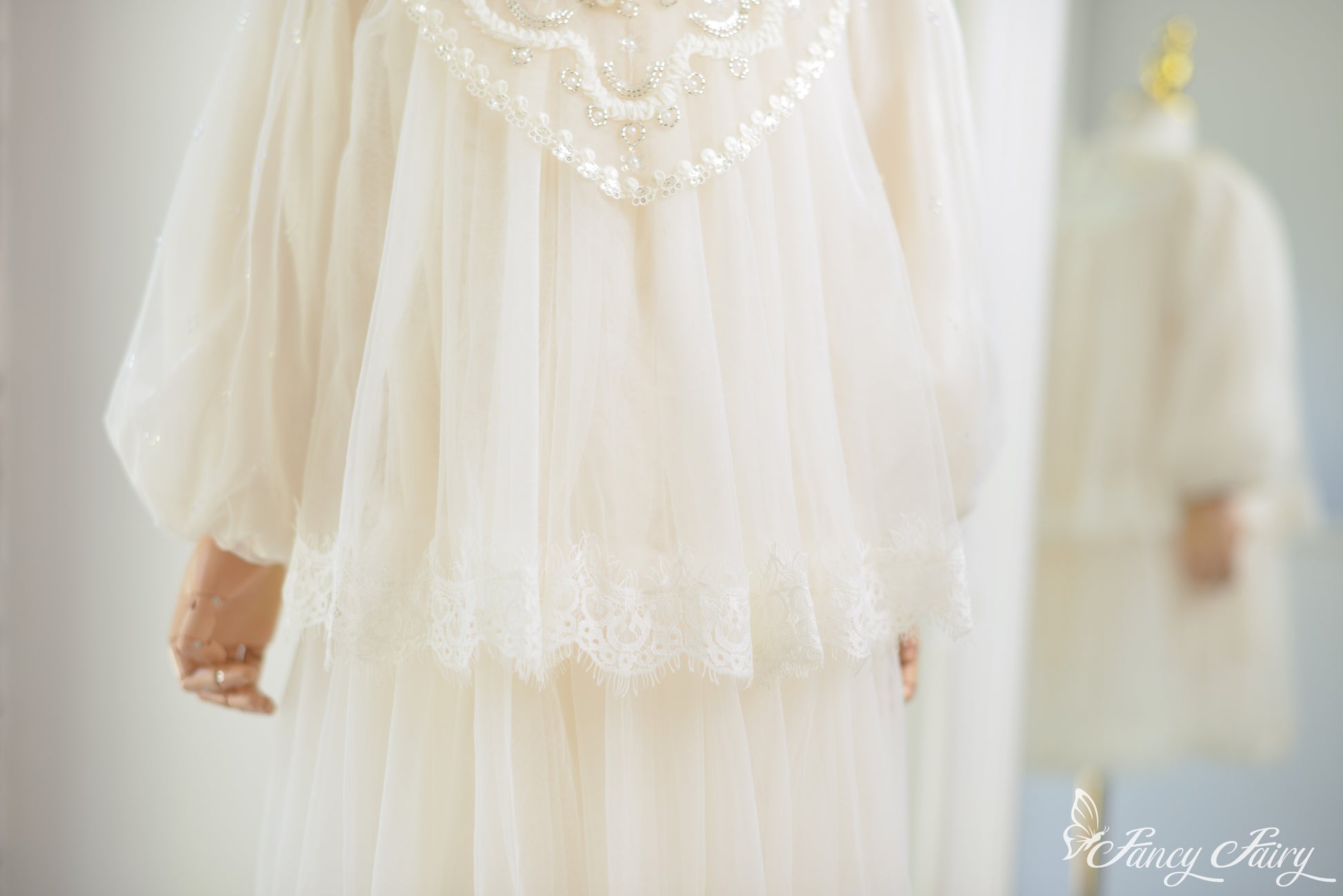 Detail of ivory lace dress puff sleeve and layered lace hem.