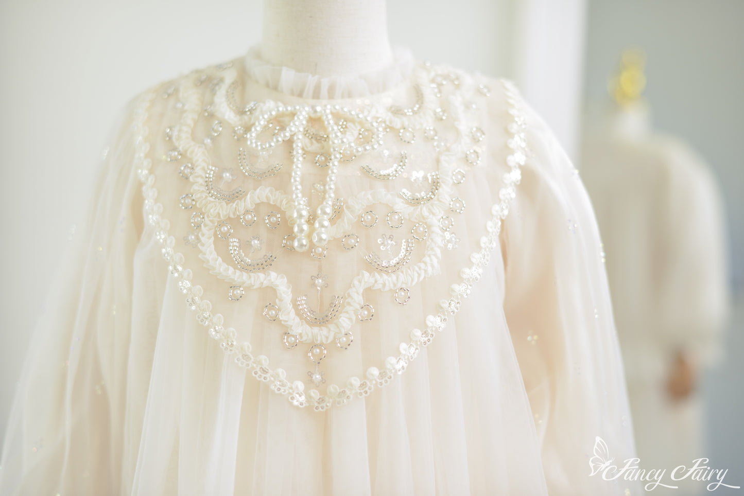 Close-up of ivory lace dress front chest panel with pearl beading and bow-tie neckline.