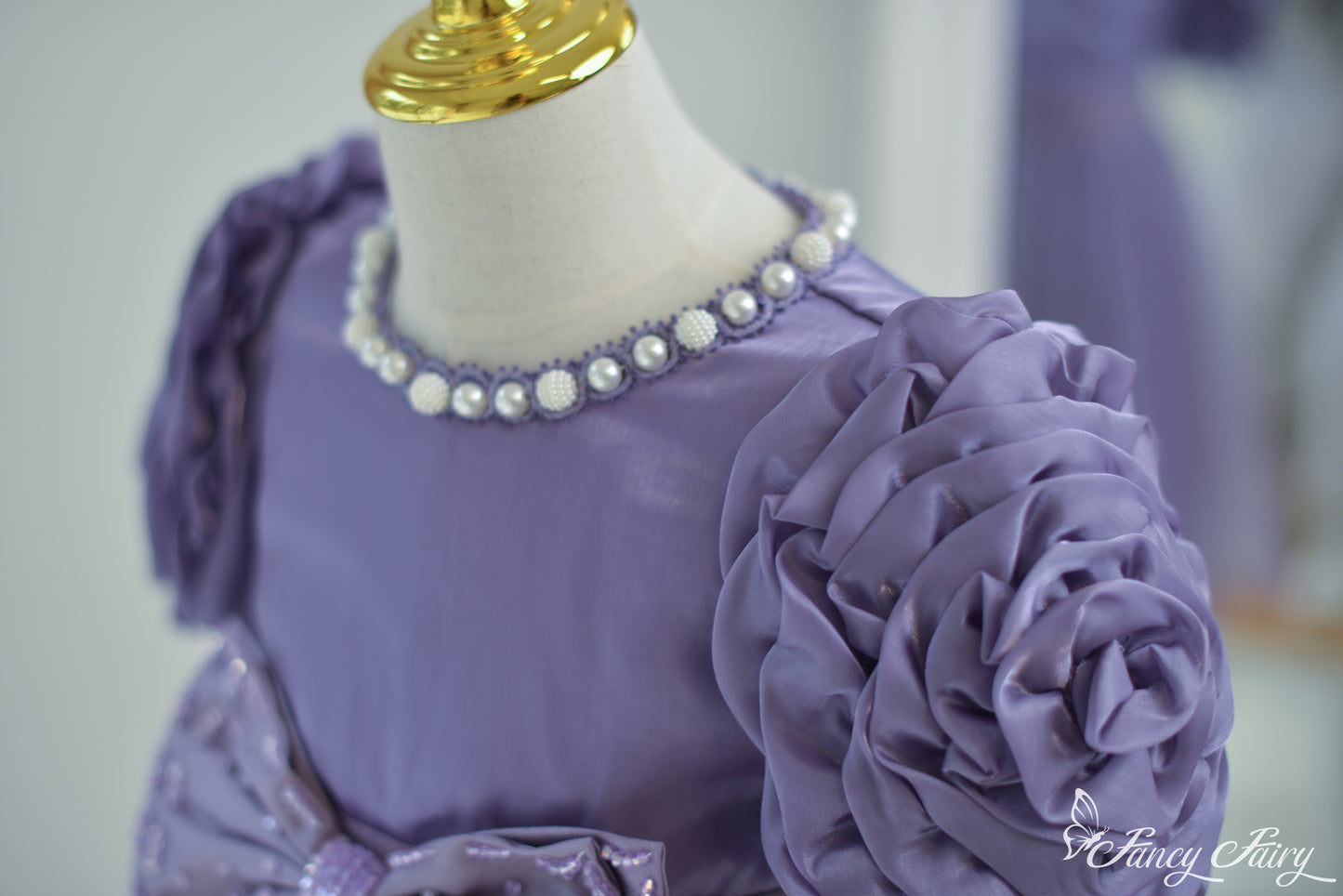 Detail of pearl beaded collar and floral sleeve texture.