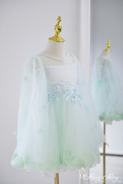 Side view of mint green girls' dress with sheer sleeves, floral embroidery, and petal hem.