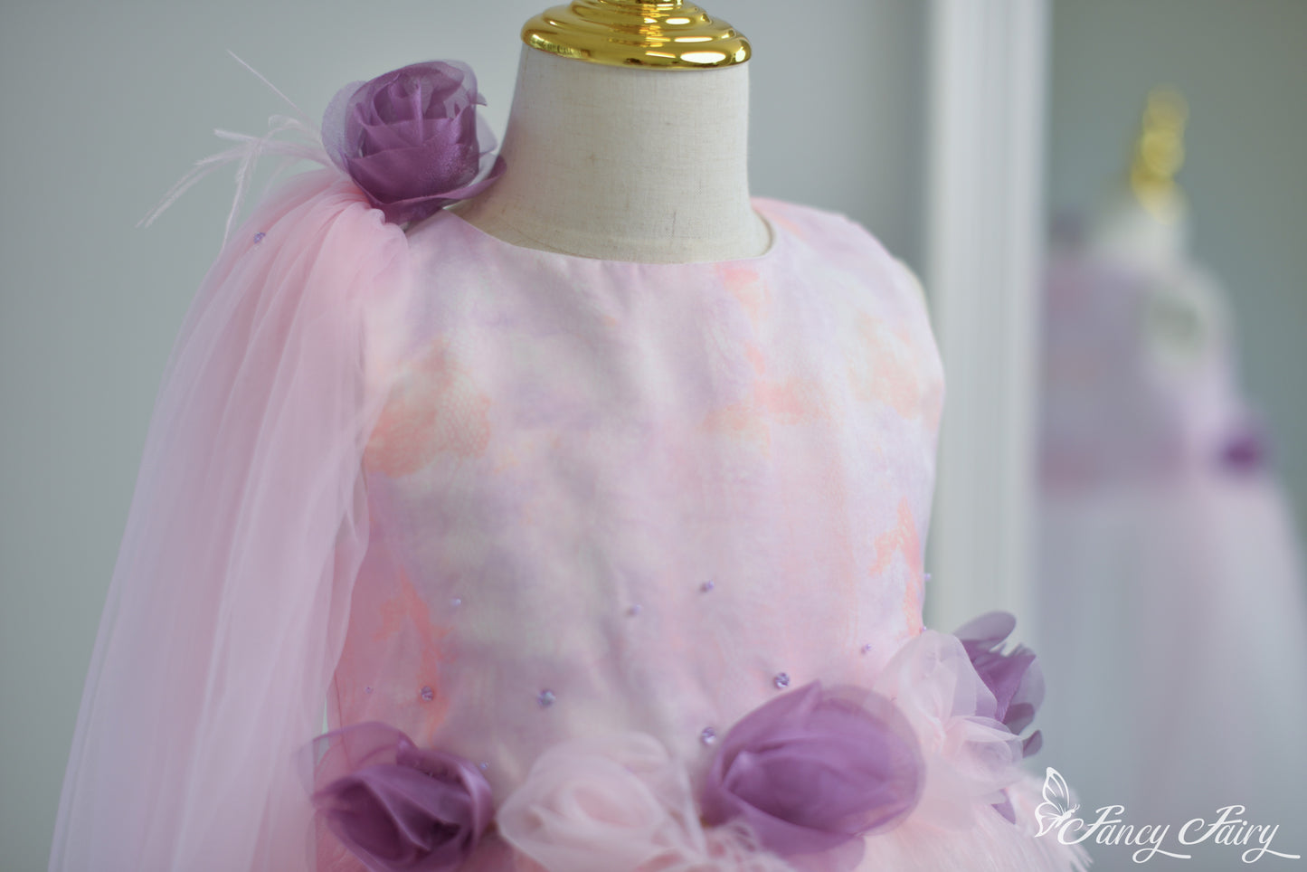 Upper front detail showing sleeveless neckline and soft tulle flower shoulder clip.