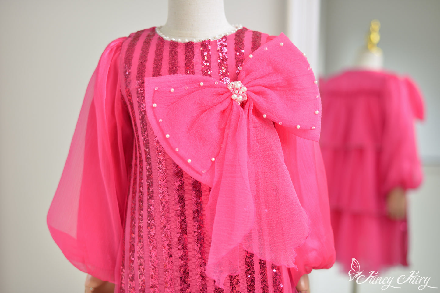 Close up of sequin stripes and pink bow with pearls. 