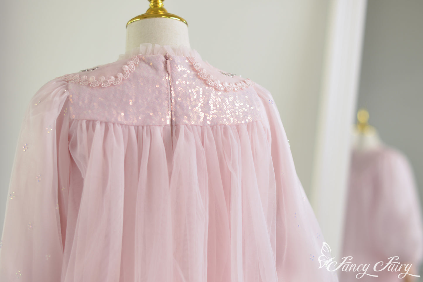 Back close-up of pink lace dress with sequin yoke, soft tulle gathering, and delicate floral trim.