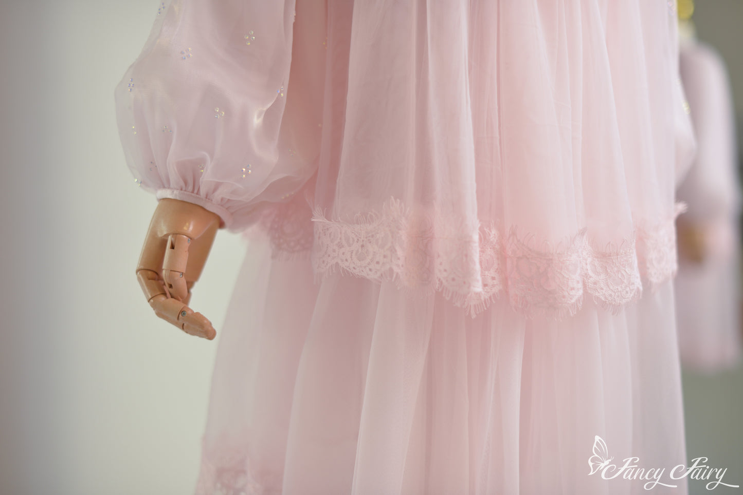 Side detail of pink lace dress puff sleeve and layered lace hem on pink dress.