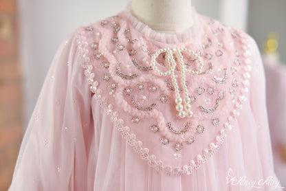 Close-up of pink lace dress front chest panel with pearl beading and bow-tie neckline.