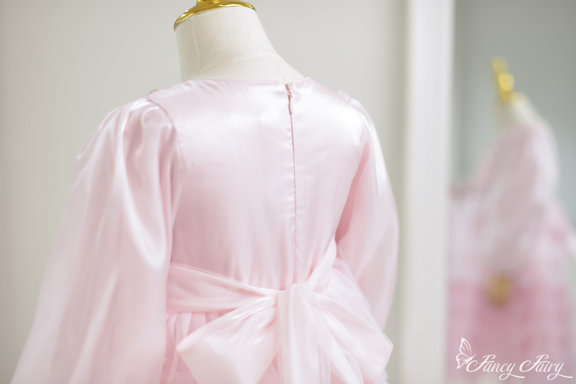 Back view of pink satin girl's dress with large bow detail.