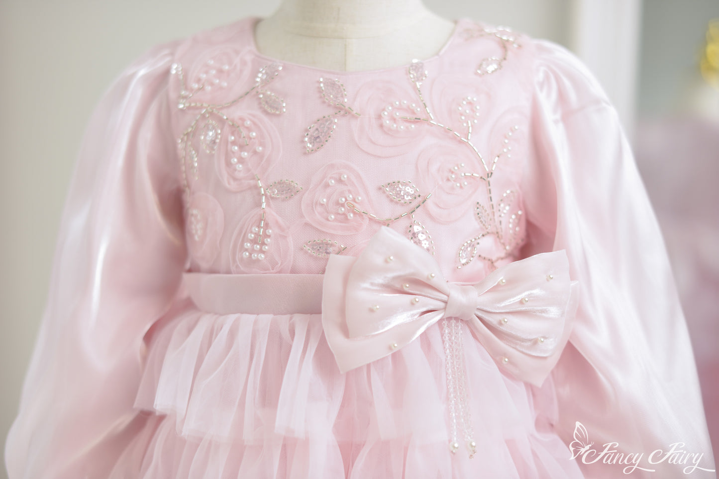 Close-up of floral embroidery with pearls and satin bow belt.