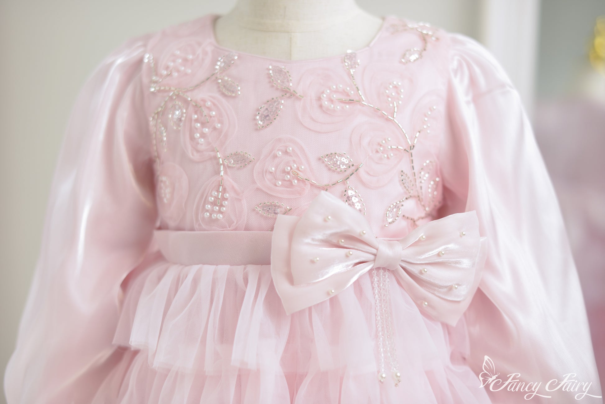 Close-up of floral embroidery with pearls and satin bow belt.