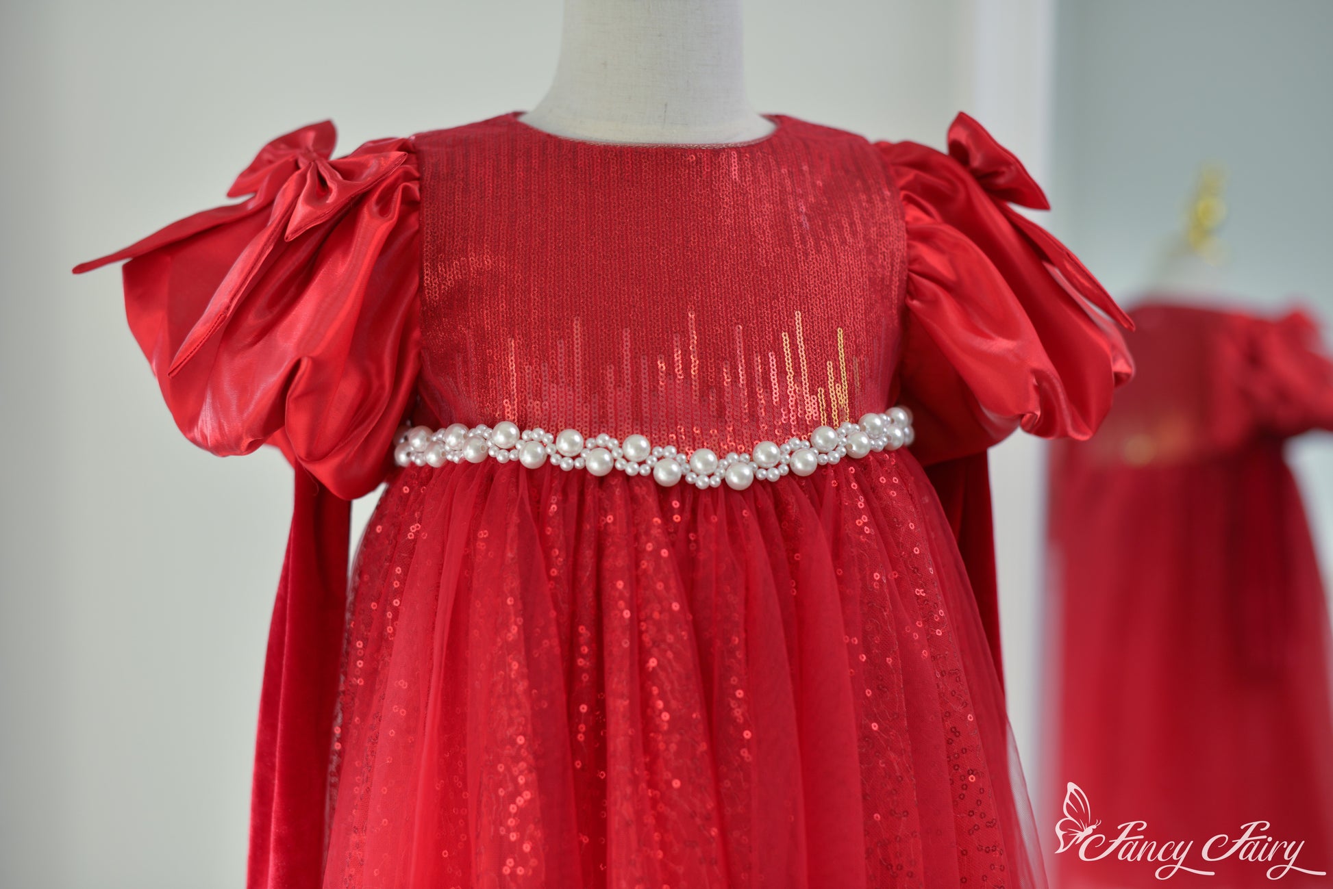 Close-up of pearl belt and shimmer detail on red tulle dress.