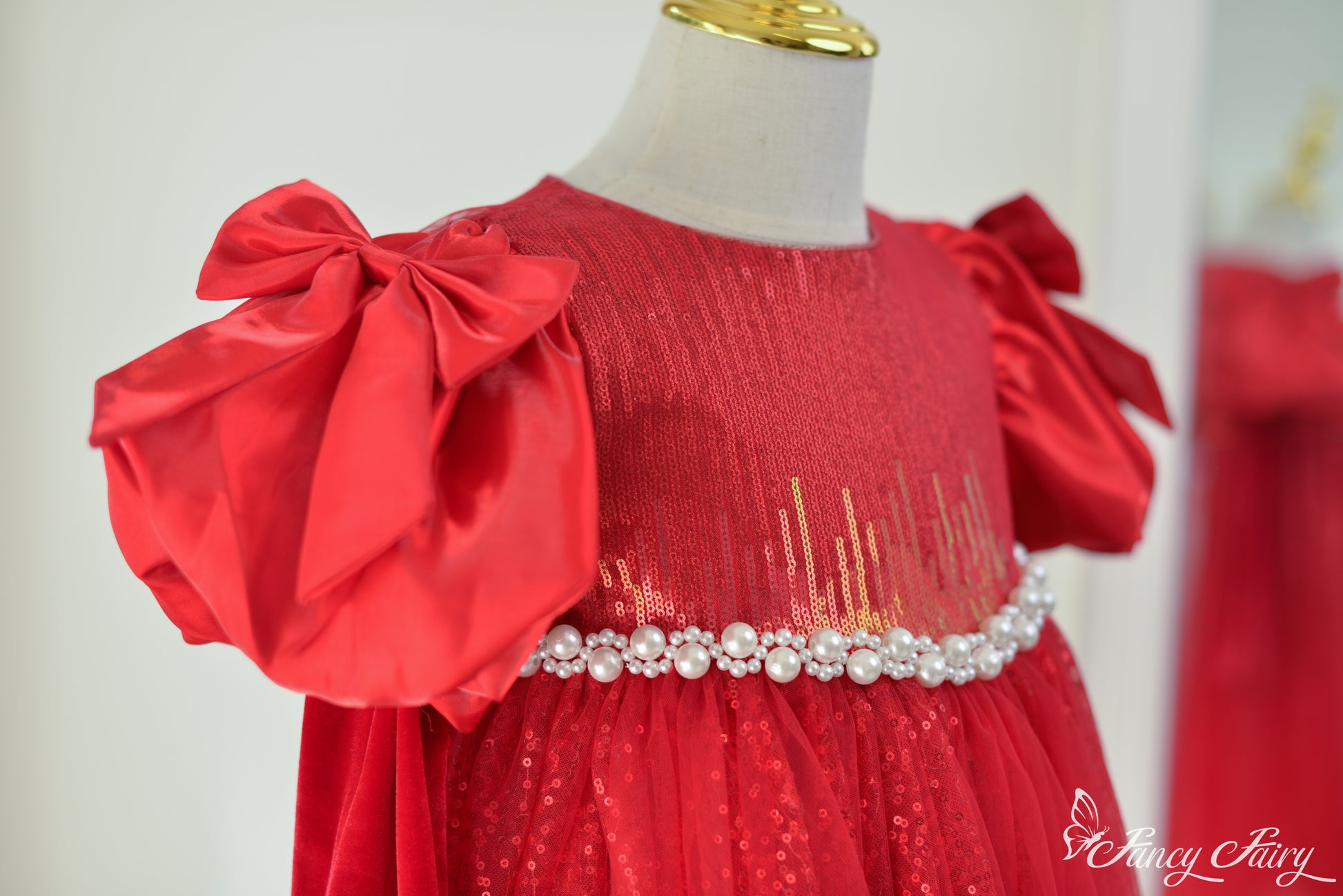 Close-up of left side showing bow sleeve and pearl belt on red tulle dress.