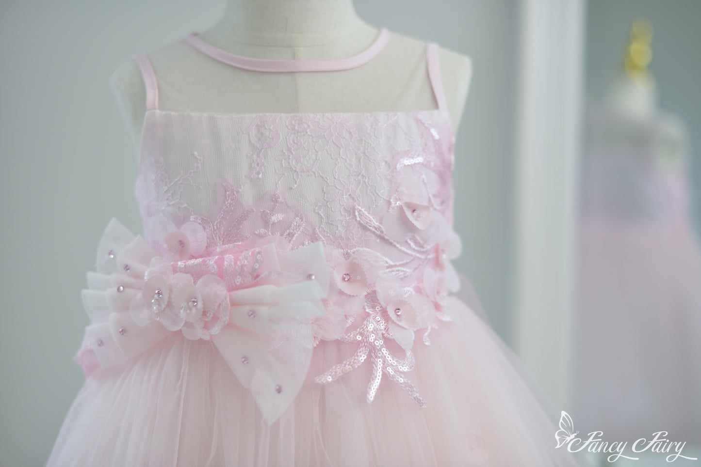 Front view of pink girls' dress with floral embroidery and double bow waist.