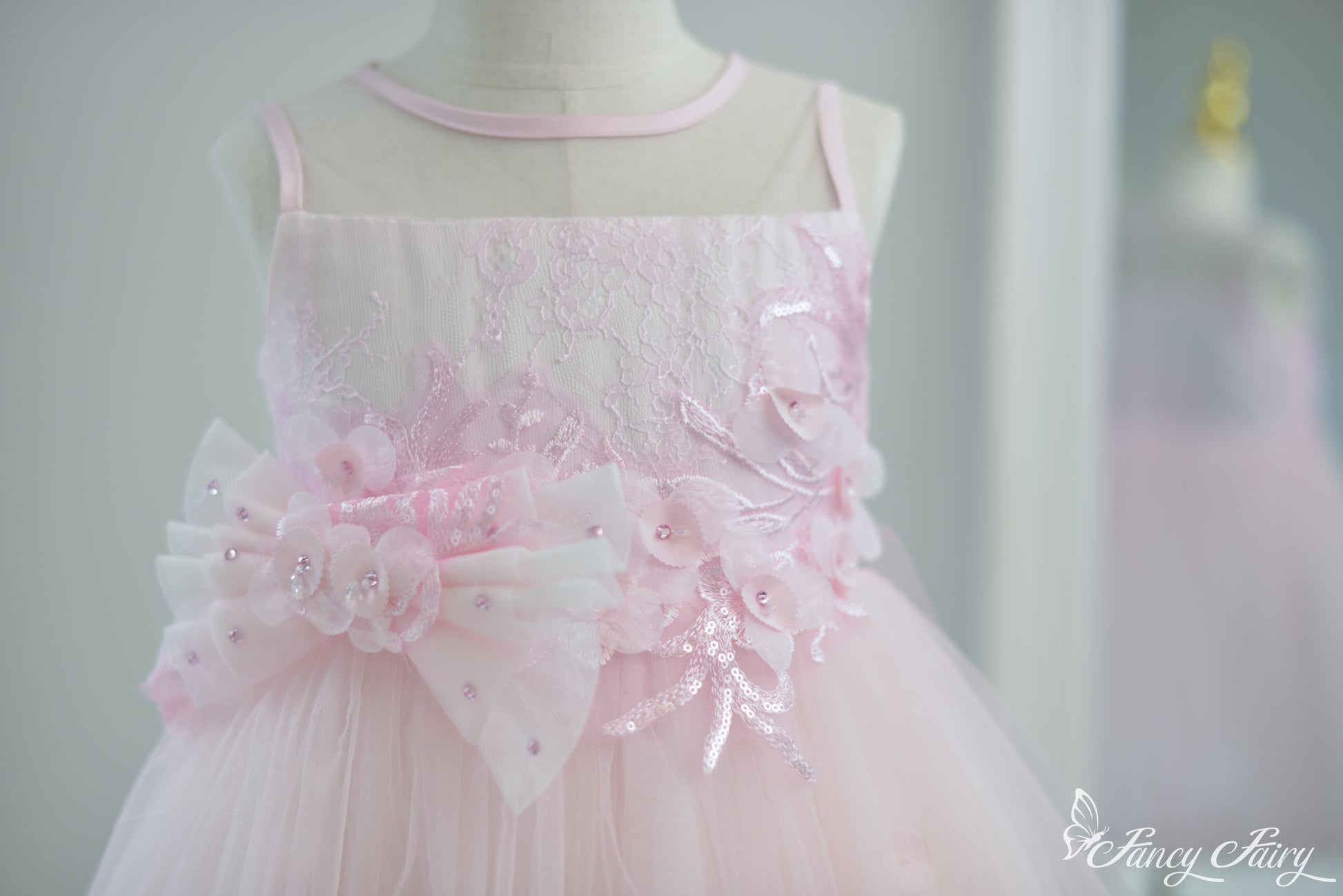 Front view of pink girls' dress with floral embroidery and double bow waist.