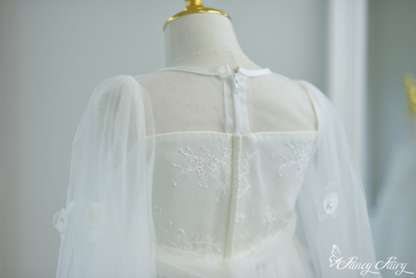 Back view of white dress showing zipper closure, floral lace bodice, and mesh sleeves.