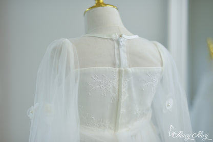 Back view of white dress showing zipper closure, floral lace bodice, and mesh sleeves.