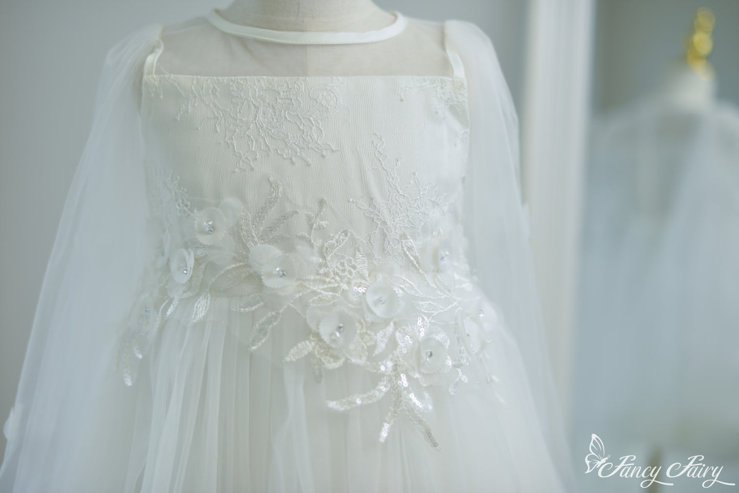 Detailed shot of white embroidered waistline with 3D flowers and sequin leaves.