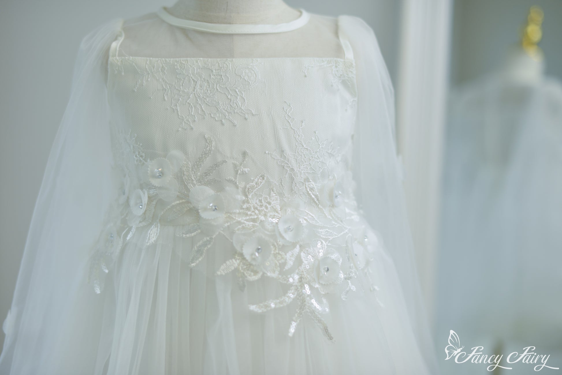 Detailed shot of white embroidered waistline with 3D flowers and sequin leaves.