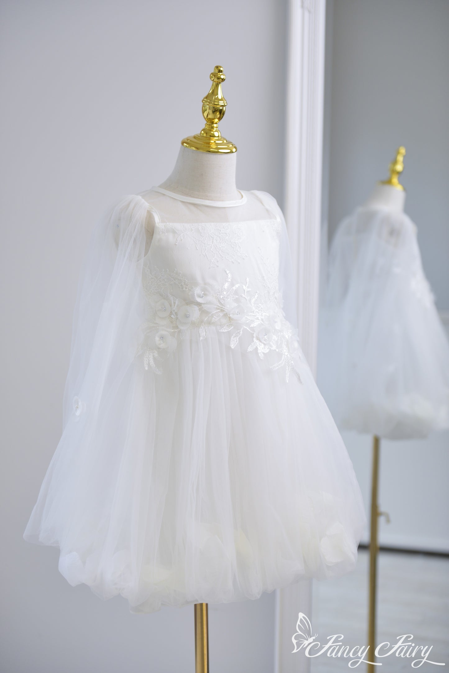 Side view of white girls' dress with floral embroidery, tulle sleeves, and petal-lined skirt