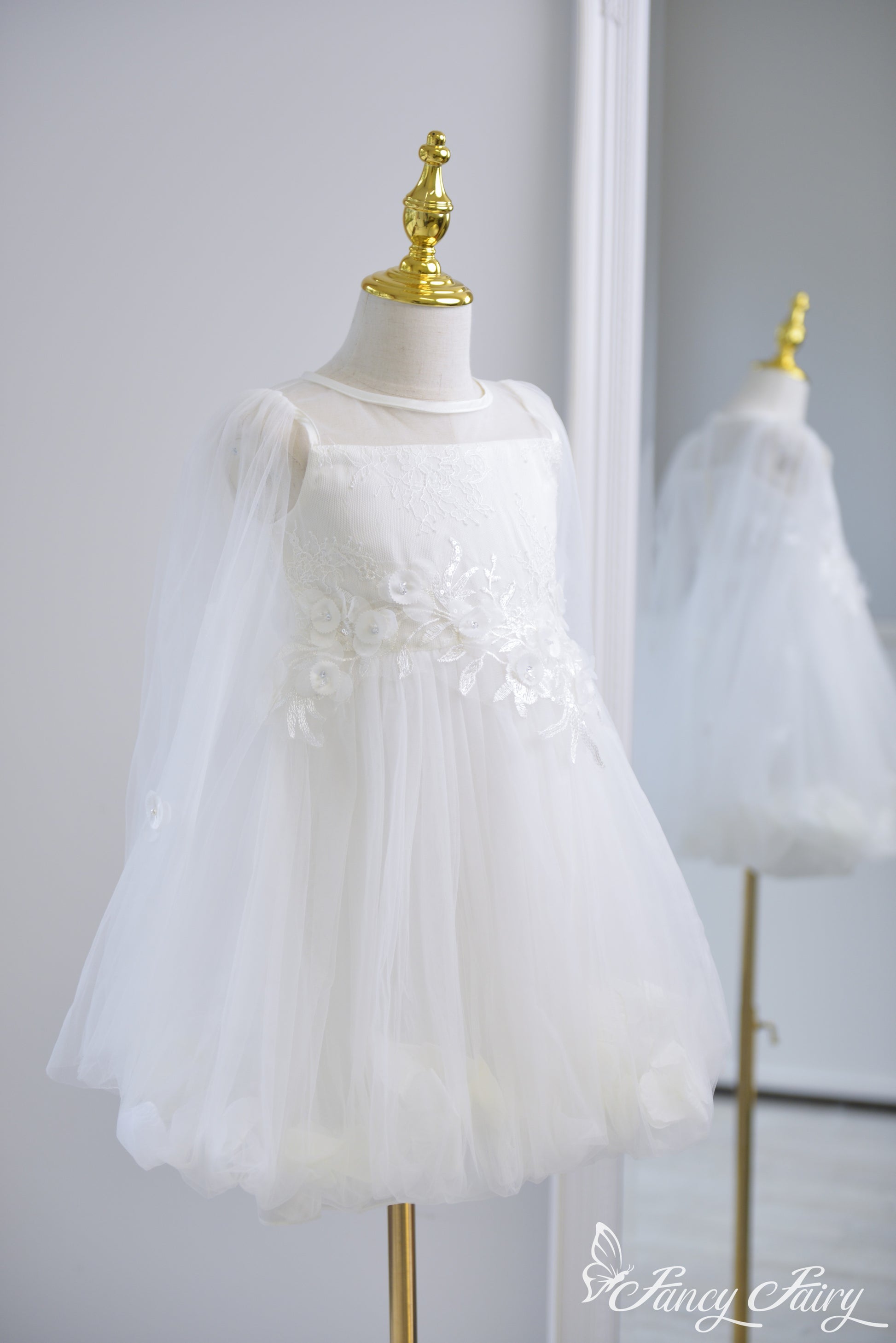 Side view of white girls' dress with floral embroidery, tulle sleeves, and petal-lined skirt